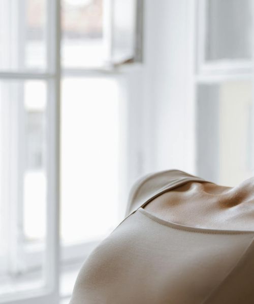 Person stretching peacefully by a window with soft morning light.